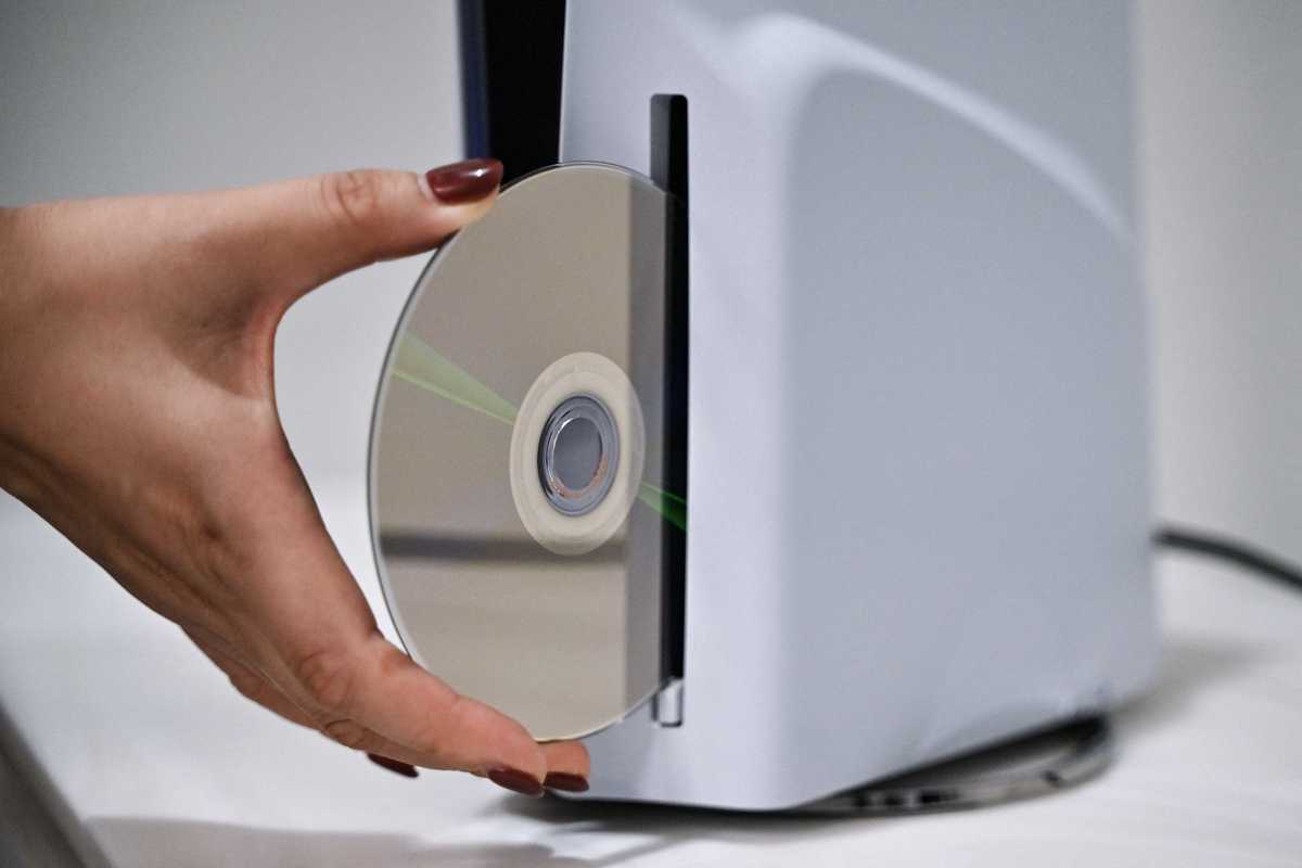 A PlayStation employee demonstrates how to put a disk into the PlayStation 5, at the Sony headquarters building in central Tokyo on November 27, 2024