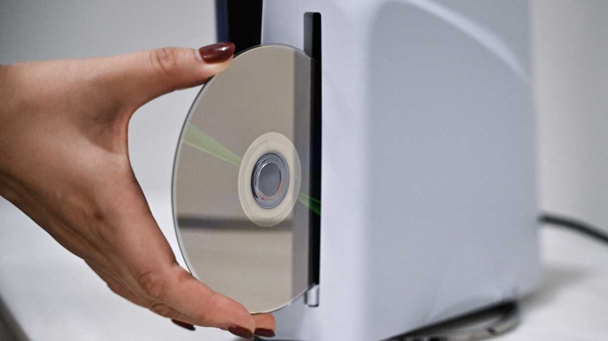 A PlayStation employee demonstrates how to put a disk into the PlayStation 5, at the Sony headquarters building in central Tokyo on November 27, 2024