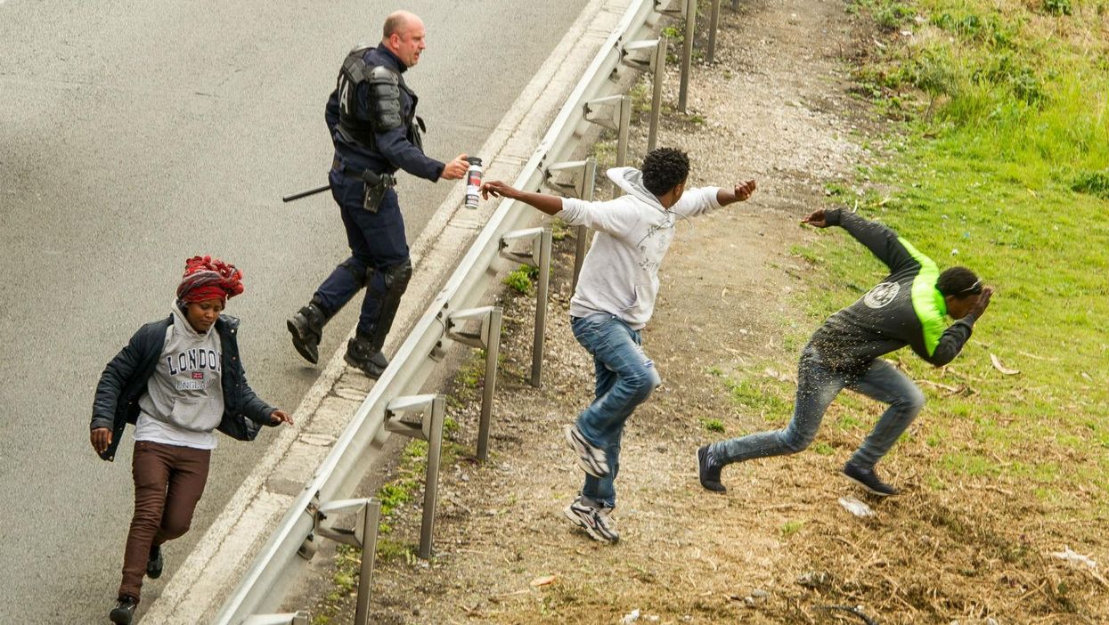 A police officer uses pepper spray on people near Calais