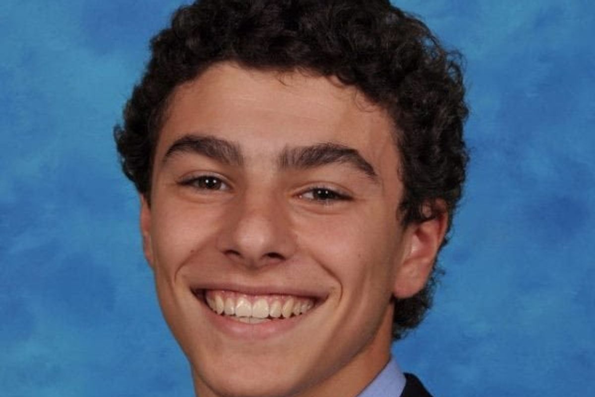 A portrait photo of Luigi Mangione smiling on a blue background