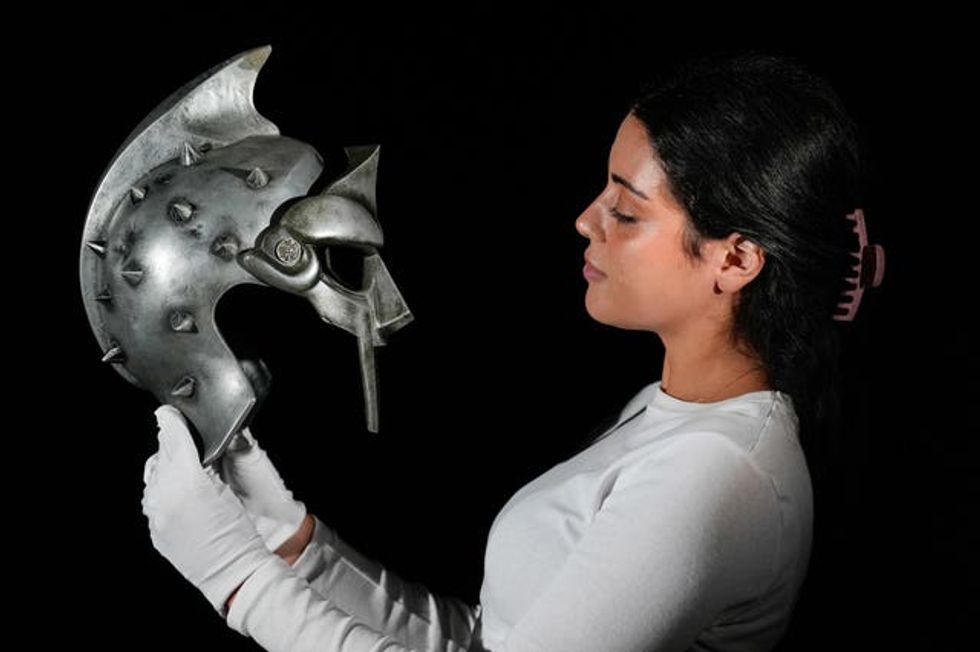 A Propstore employee holds Maximus\u2019 (Russell Crowe) arena helmet and mask