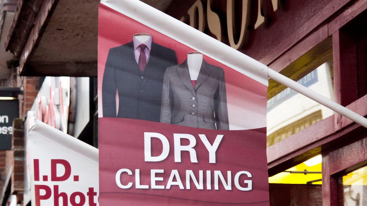 A red Timpson dry cleaning advertising banner, showing two suit jackets, outside a branch.