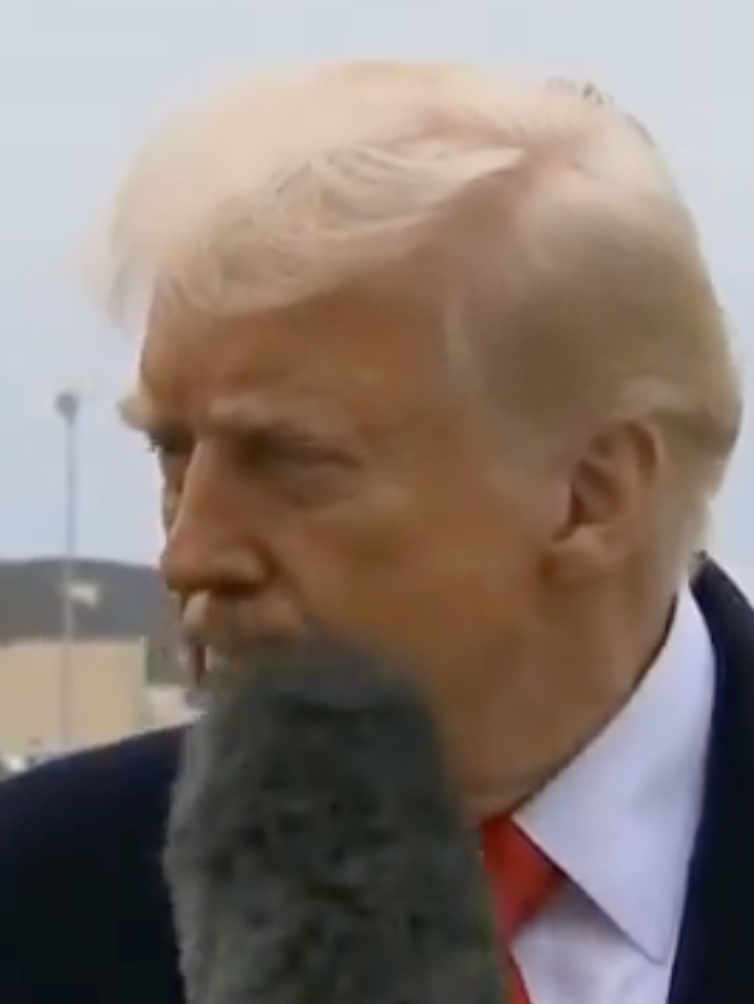 A screenshot of a video showing Donald Trump getting hit in the face with a microphone from a reporter
