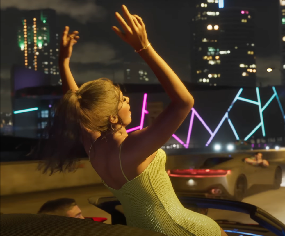 A screenshot of a woman standing in a car with its roof down with her arms in the air from the GTA 6 trailer