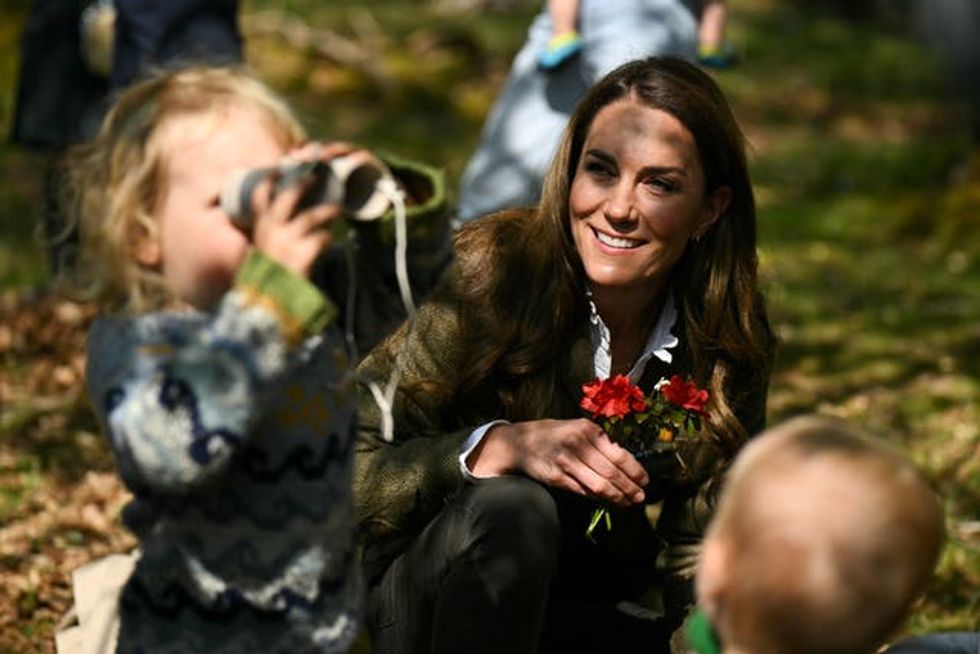 A smiling Princess of Wales watching a young girl using binoculars made from cardboard