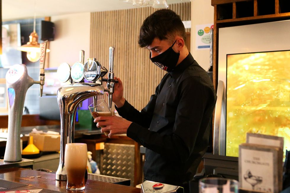 A staff member of The Churchgate pub pours a pint for a customer in Bolton, England