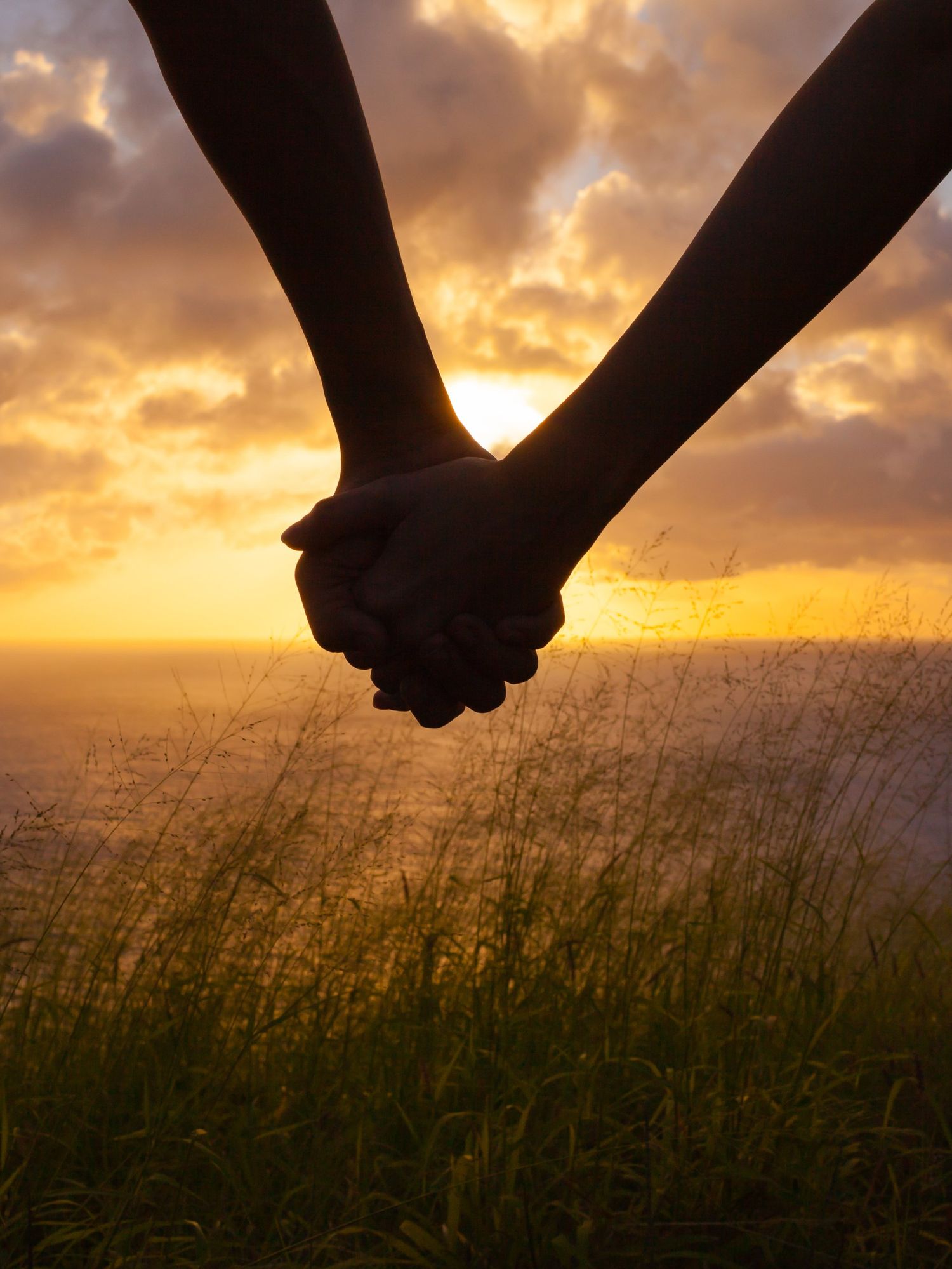 A stock image of a couple holding hands at sunset