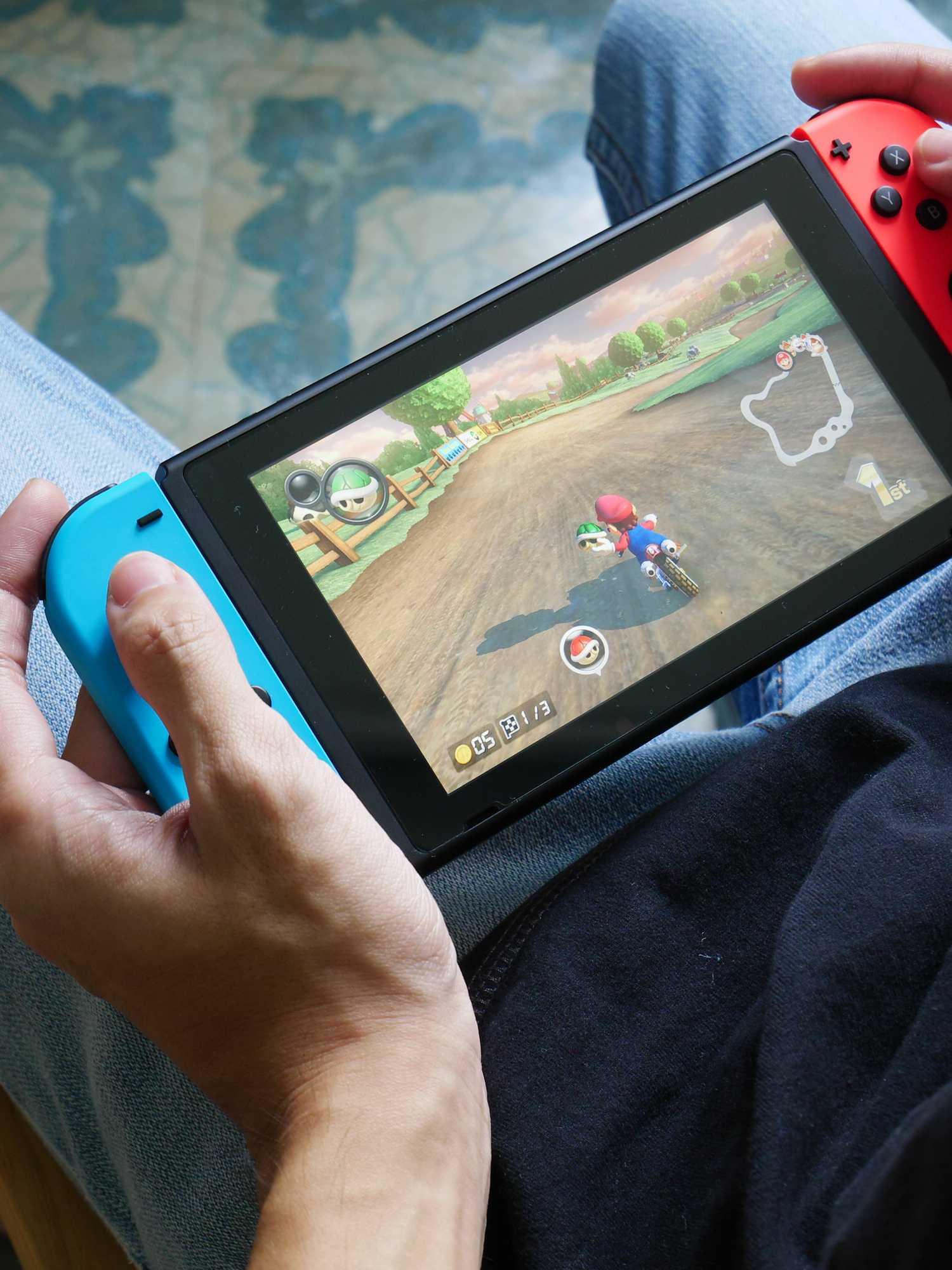 A stock image of a man playing Mario Kart 8 Deluxe on Nintendo Switch