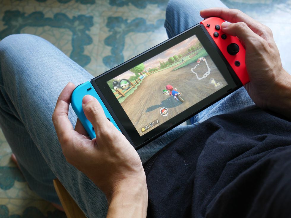 A stock image of a man playing Mario Kart 8 Deluxe on Nintendo Switch