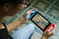 A stock image of a man playing Mario Kart on Nintendo Switch