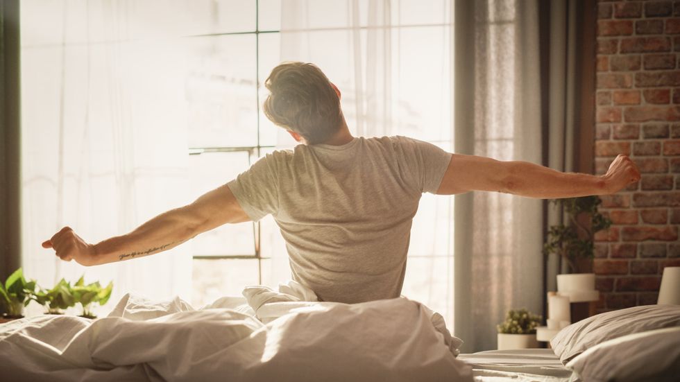 A stock image of a man stretching after waking up