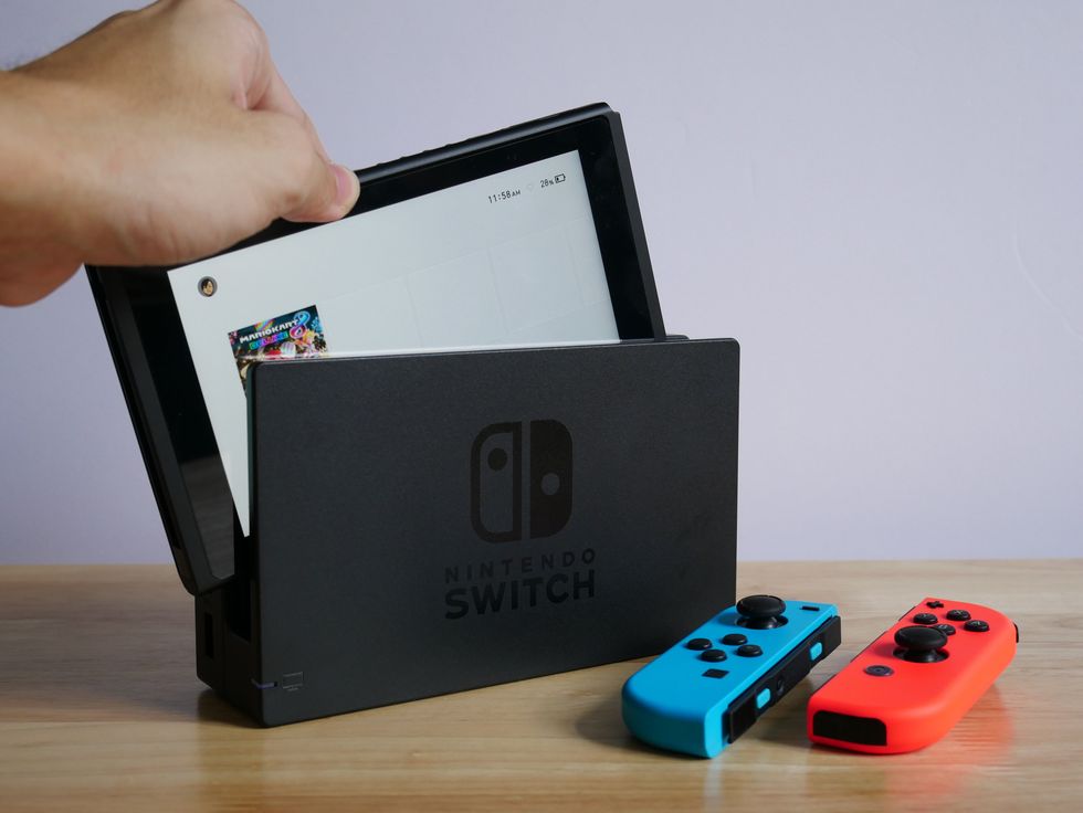 A stock image of a Nintendo Switch console on a wooden table