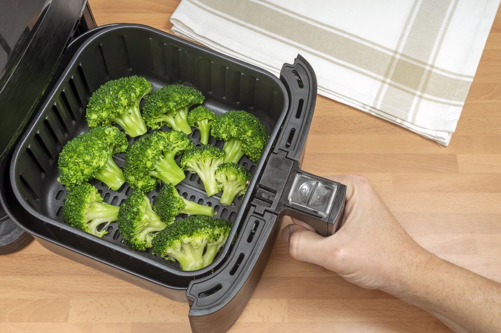 A stock image of broccoli being cooked in an air fryer