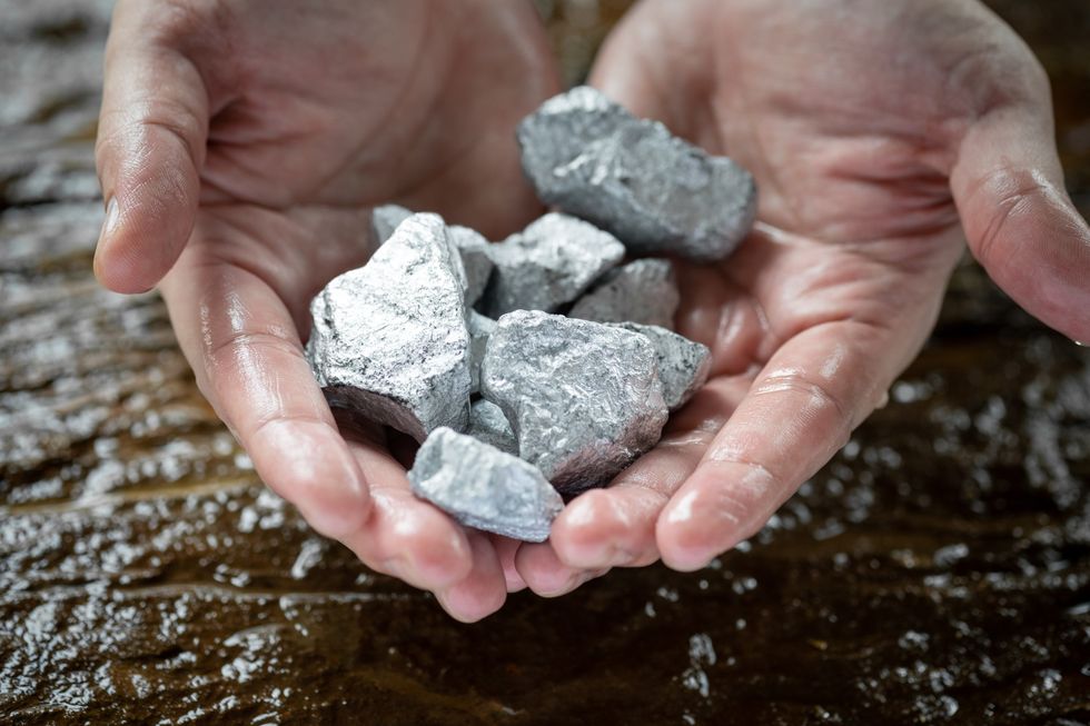 A stock image of hands holding silver, or platinum, or rare earth mineral