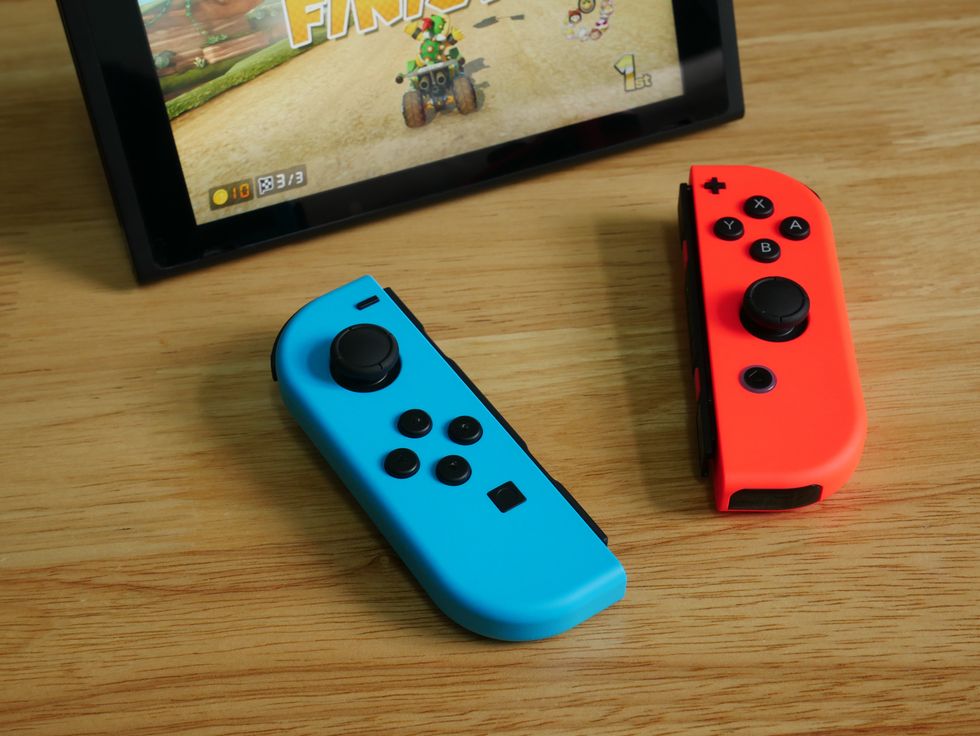 A stock image of the Nintendo Switch and Joy-Cons on a wooden table
