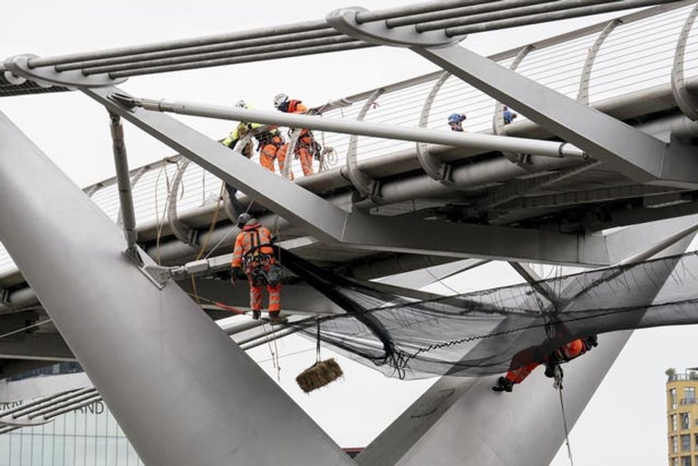 A straw bale is suspended from London\u2019s Millennium Bridge as work is undertaken on the structure