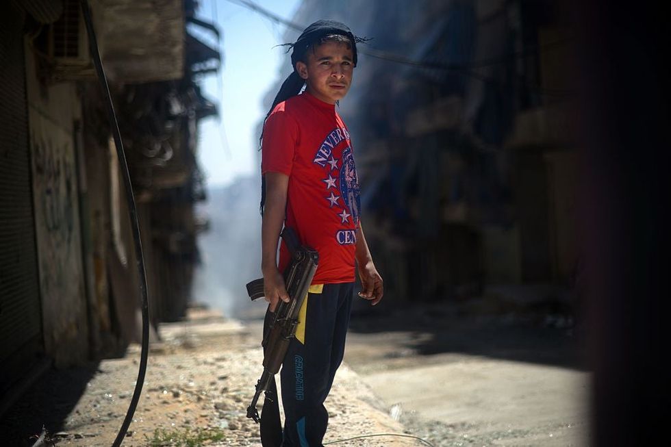 A Syrian boy holds an AK-47 assault rifle in the majority-Kurdish Sheikh Maqsud district of the northern Syrian city of Aleppo on April 14, 2013 Picture: