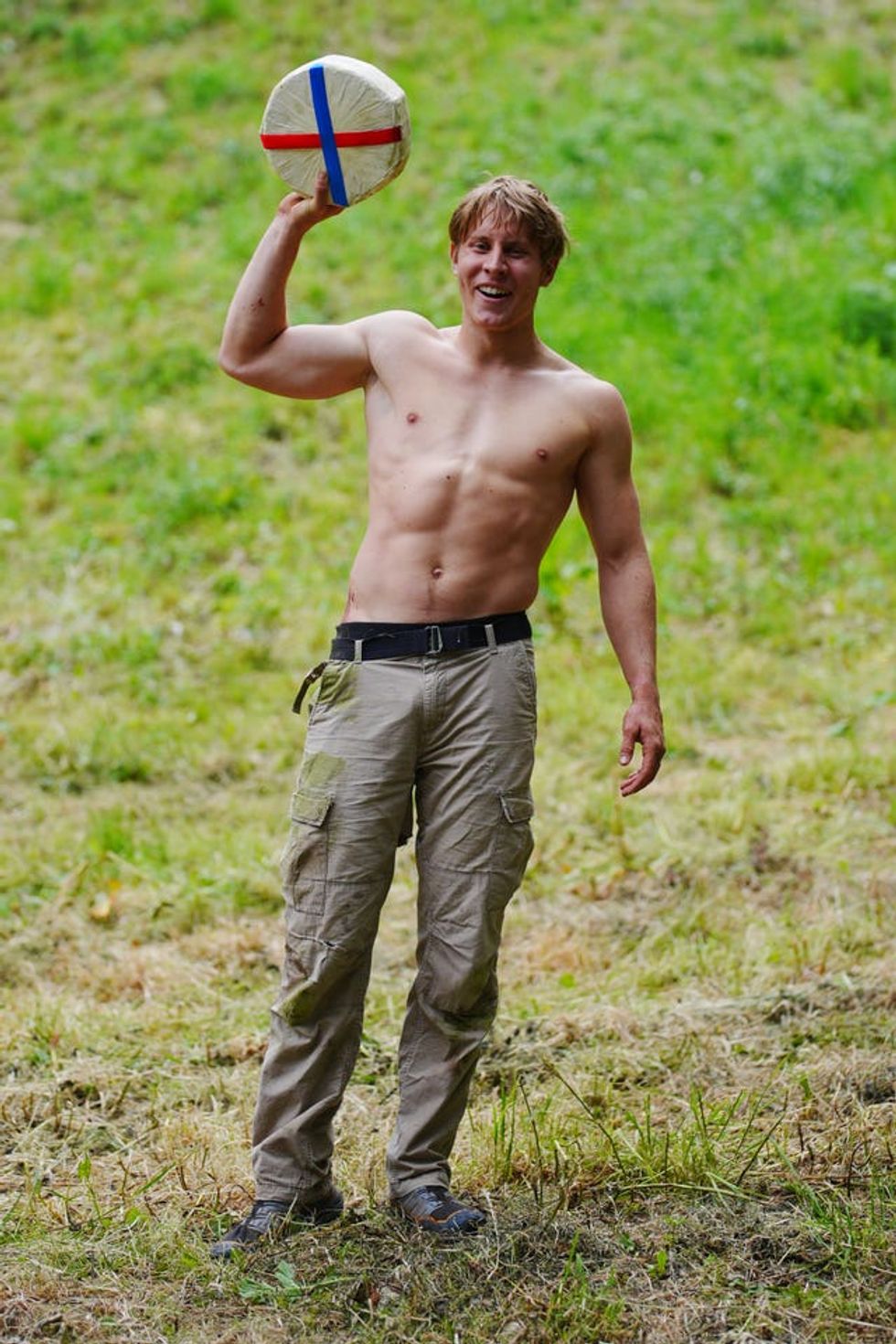 A topless Tom Kopke holding the cheese aloft in his right hand