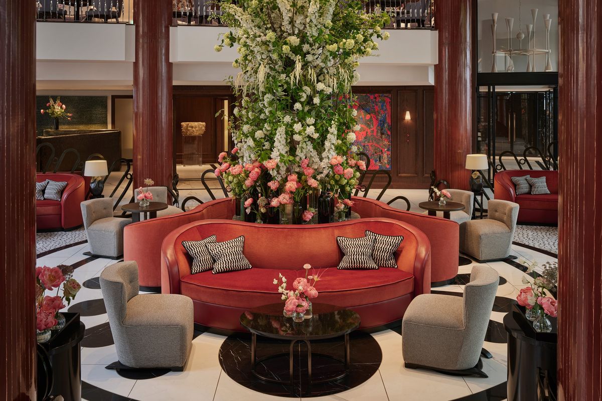 A view of the lobby, featuring a number of sofas in coral and grey, as well as a floral decoration centrepiece.