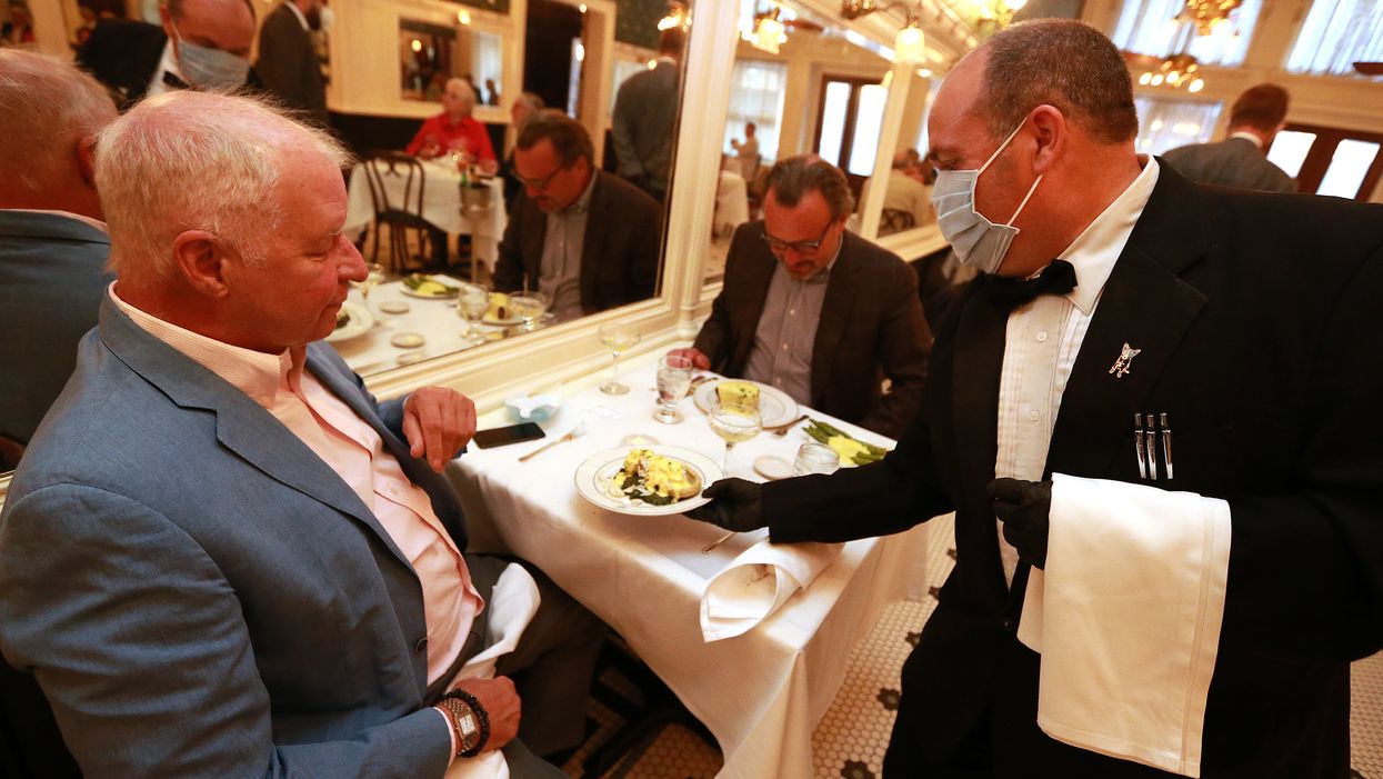 A waiter delivers food to a customer during dinner at Galatoire's Restaurant on May 22, 2020 in New Orleans, Louisiana. The City of New Orleans