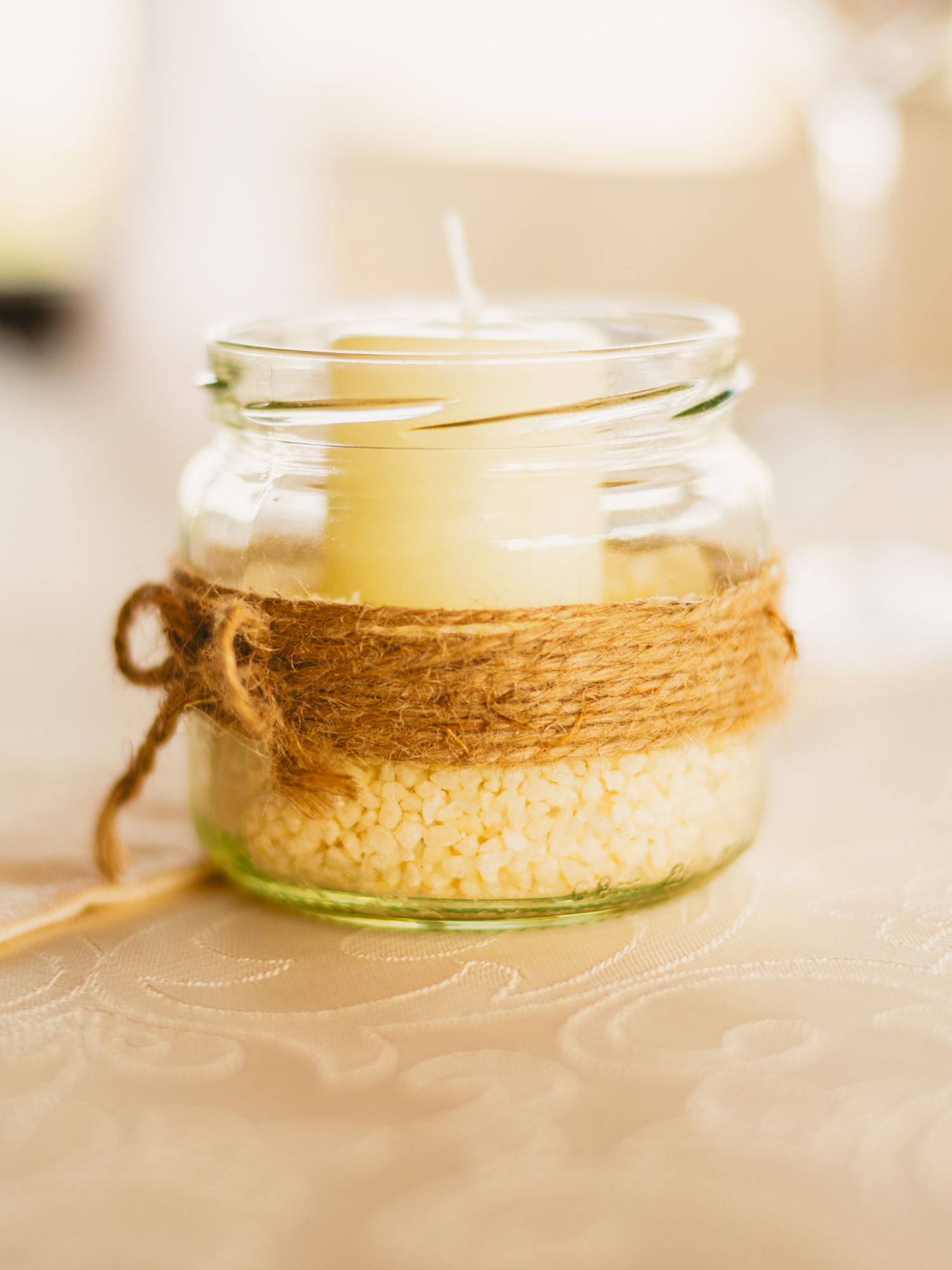 A white candle in a jar with string wrapped around it.