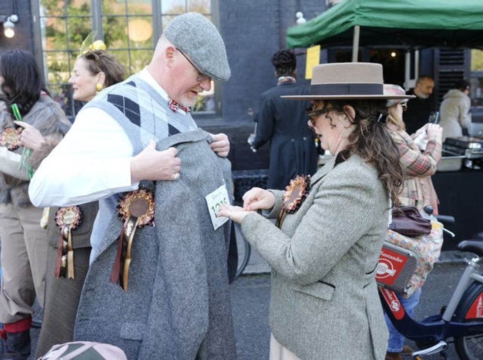 A woman affixing a race number to a tweed coat