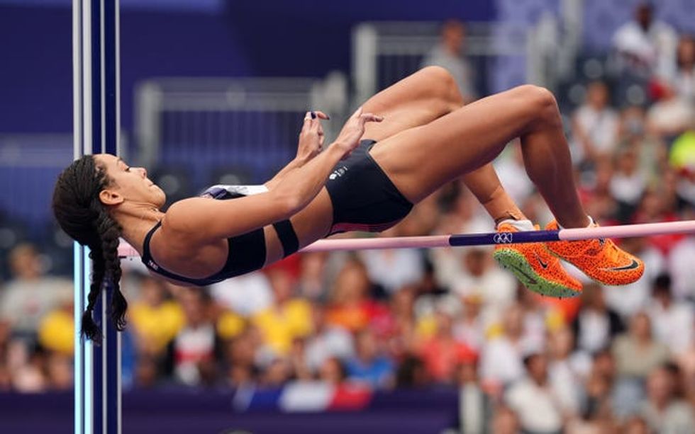 A woman back flips over a high jump bar