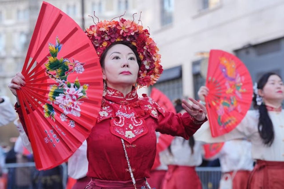A woman dressed in red waves two fans