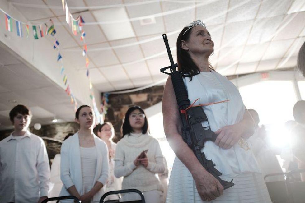 A woman holds an AR-15 rifle during a ceremony