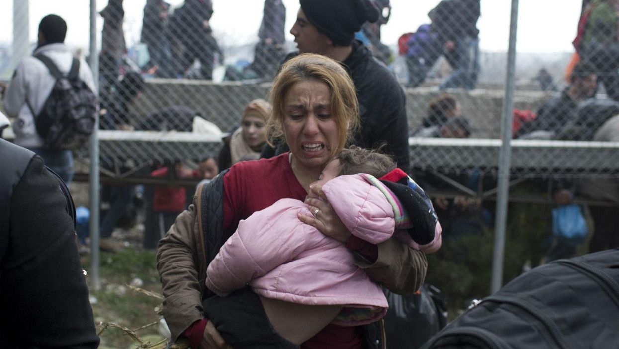 A woman holds her child as she runs away from police firing tear gas on the Greek-Macedonian border, 29th Febraury 2016. Picture: Petros Giannakouris/AP