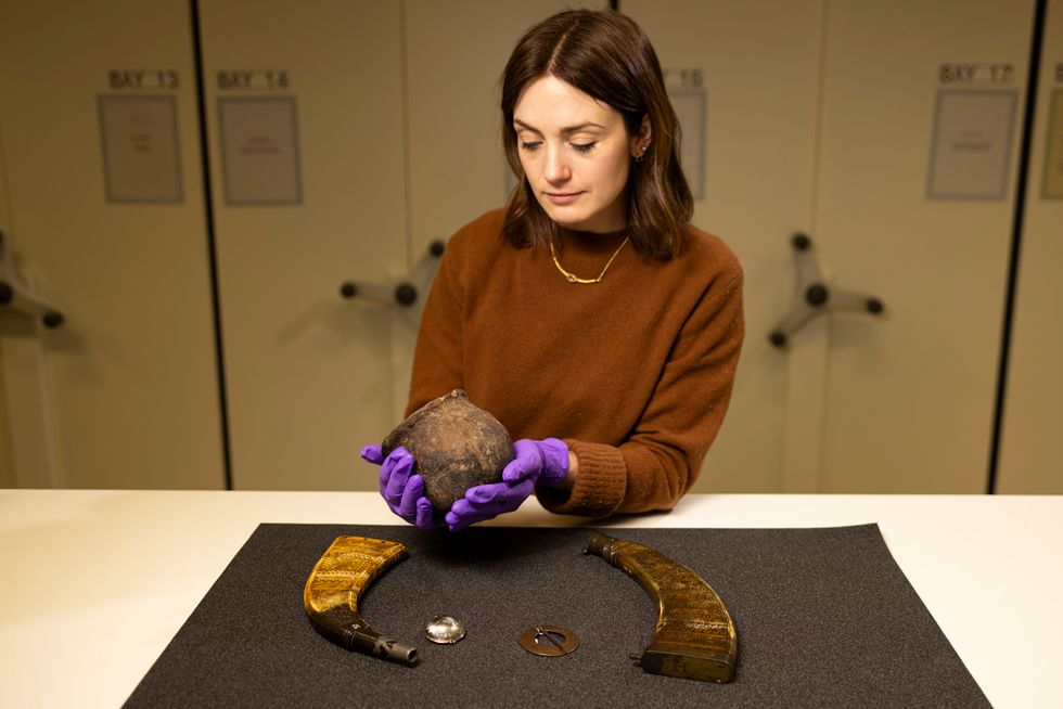 A woman in gloves with artefacts including a pot and horns