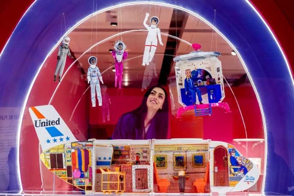 A woman looking at a Barbie exhibition