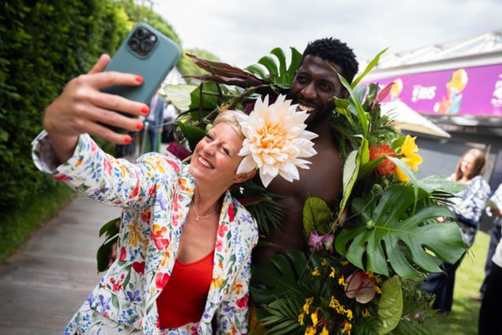 A woman takes a selfie with a man dressed in plants at the RHS Chelsea Flower Show