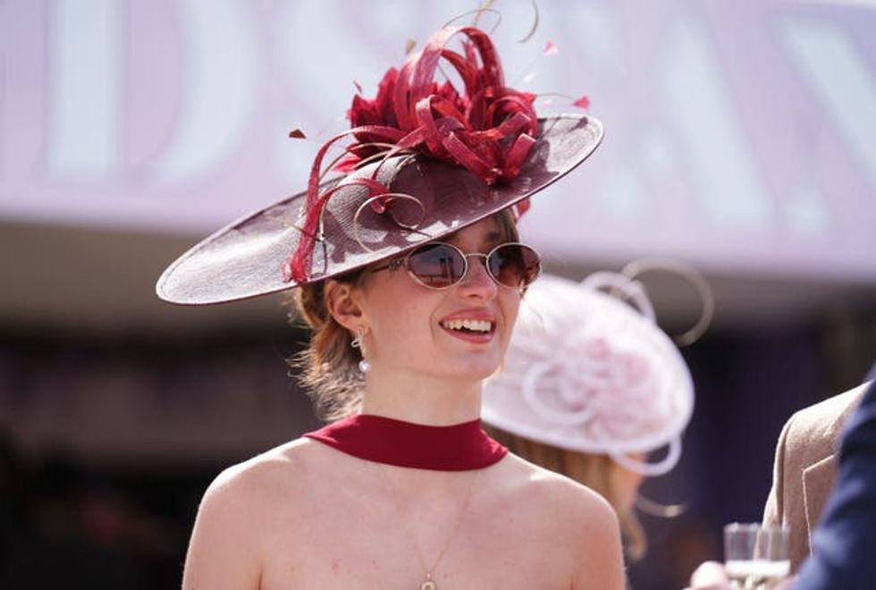 A woman wearing a saucer hat with curled ribbons