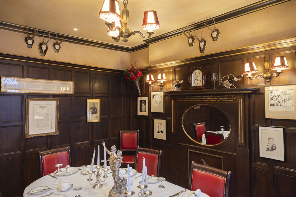 A wood panelled room with a formal dining table and pictures on the wall named after John Betjeman