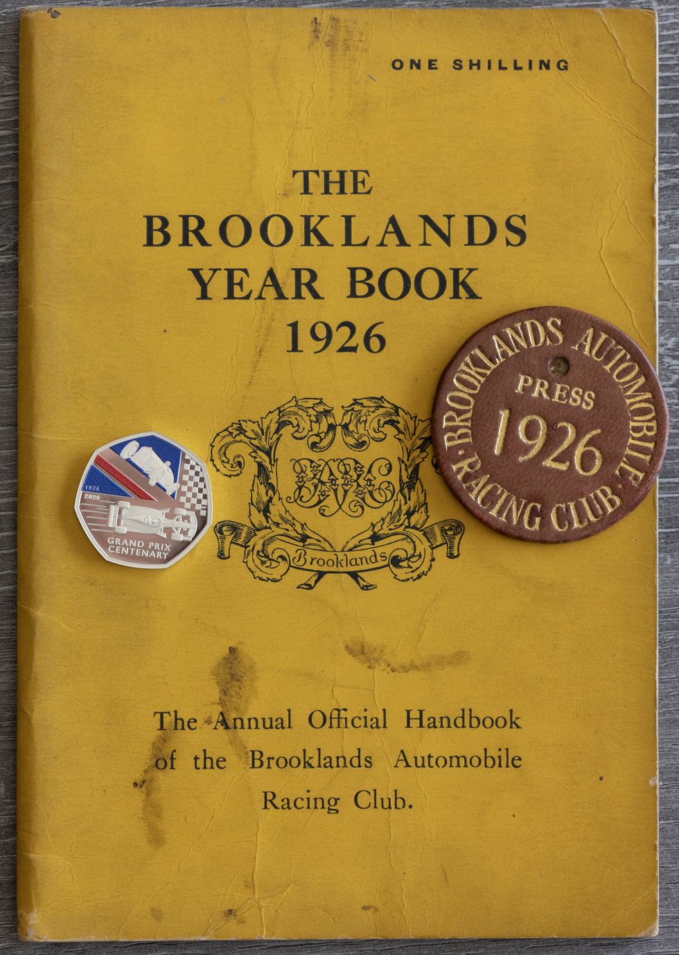 A yellow Brooklands year book 1926, with the new 50p sitting on top of it