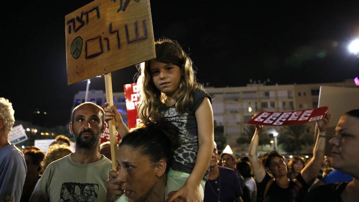 A young girl holds a placard reading in Hebrew: 'I want peace'