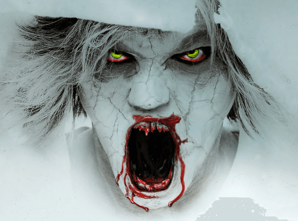 A zombie with a white, chalky face and cracked skin, with bloody, jagged teeth, yellow eyes and matted hair, screams at the camera.