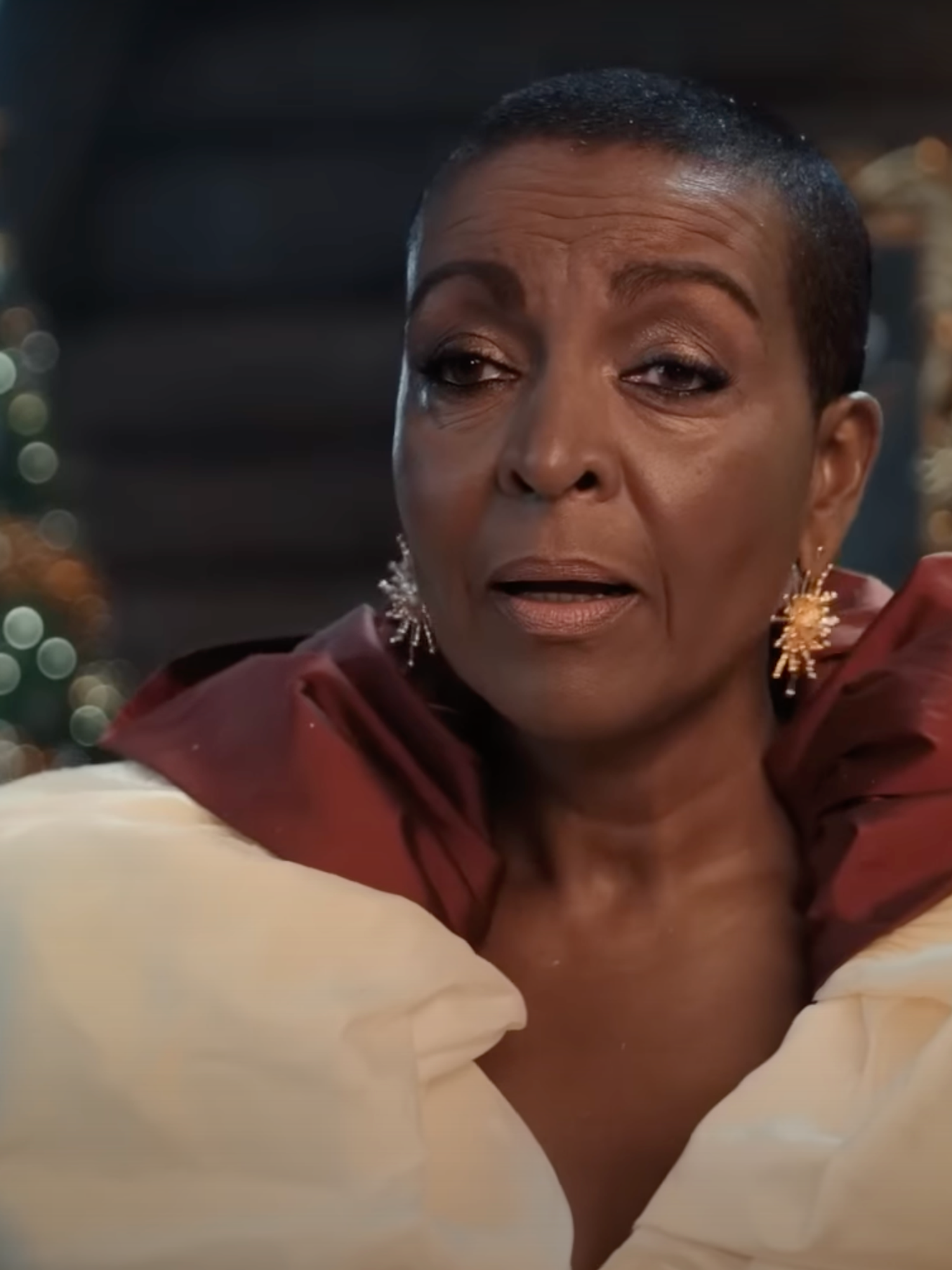 Adjoa Andoh, a Black woman with short black hair, wearing a puffy white and red coat in Boots' Christmas advert.