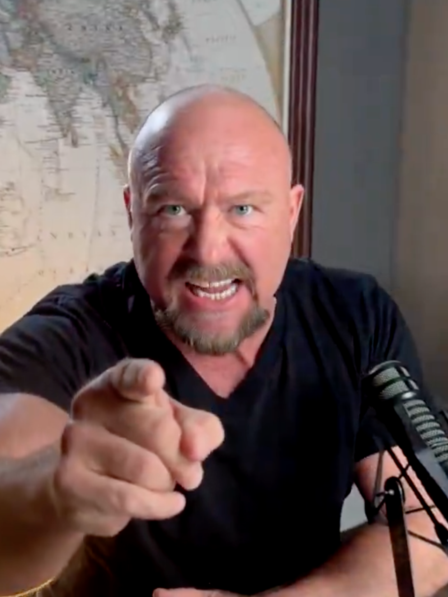 Alex Jones, a bald white man, angrily pointing at the camera.