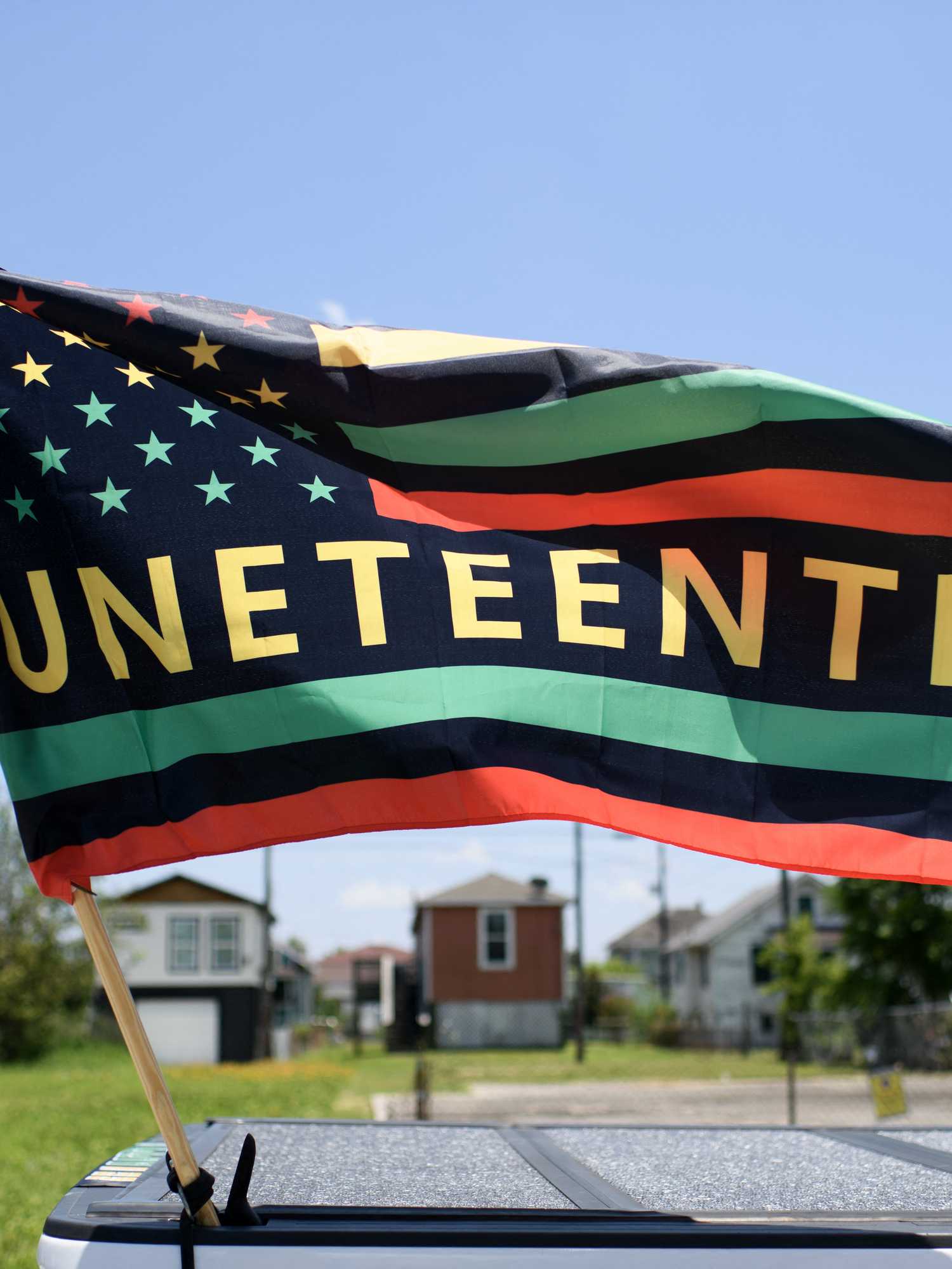 An American flag, with the word 'Juneteeth' in the middle of it in all caps and yellow. The rest of the US flag is in red, yellow and green.