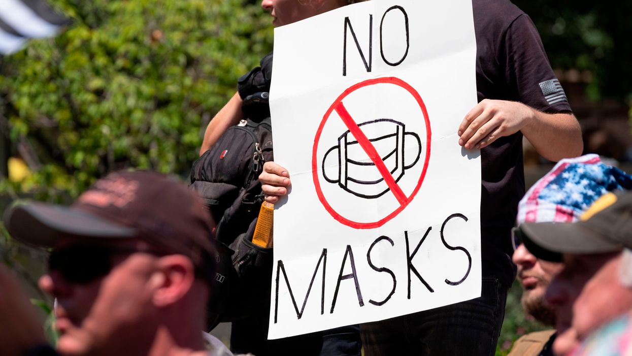 An anti-mask protestor holds up a sign in front of the Ohio Statehouse during a right-wing protest "Stand For America Against Terrorists and Tyrants"