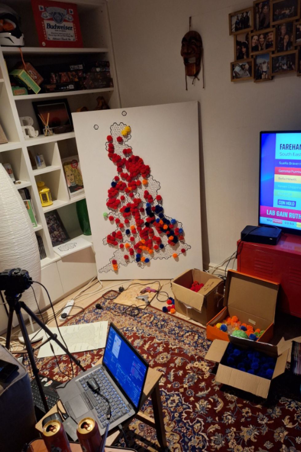 An election map covered in pom poms next to a TV