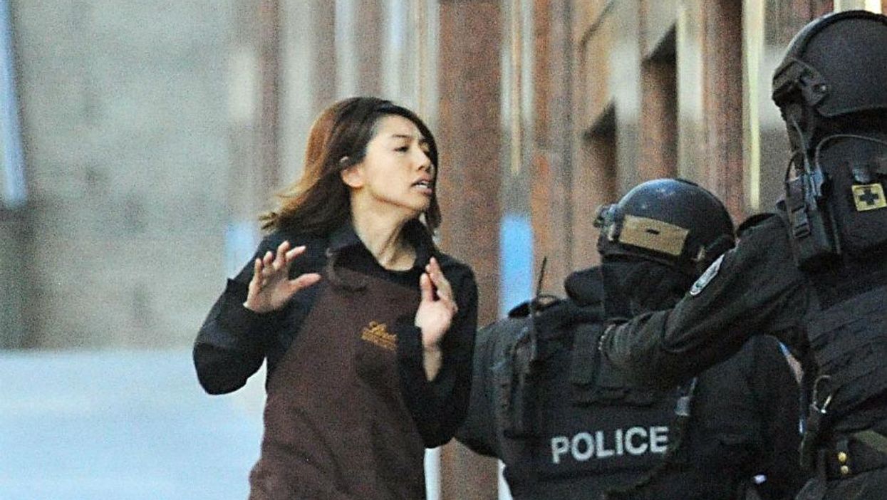 An employee from the Lindt cafe runs towards armed police in central Sydney