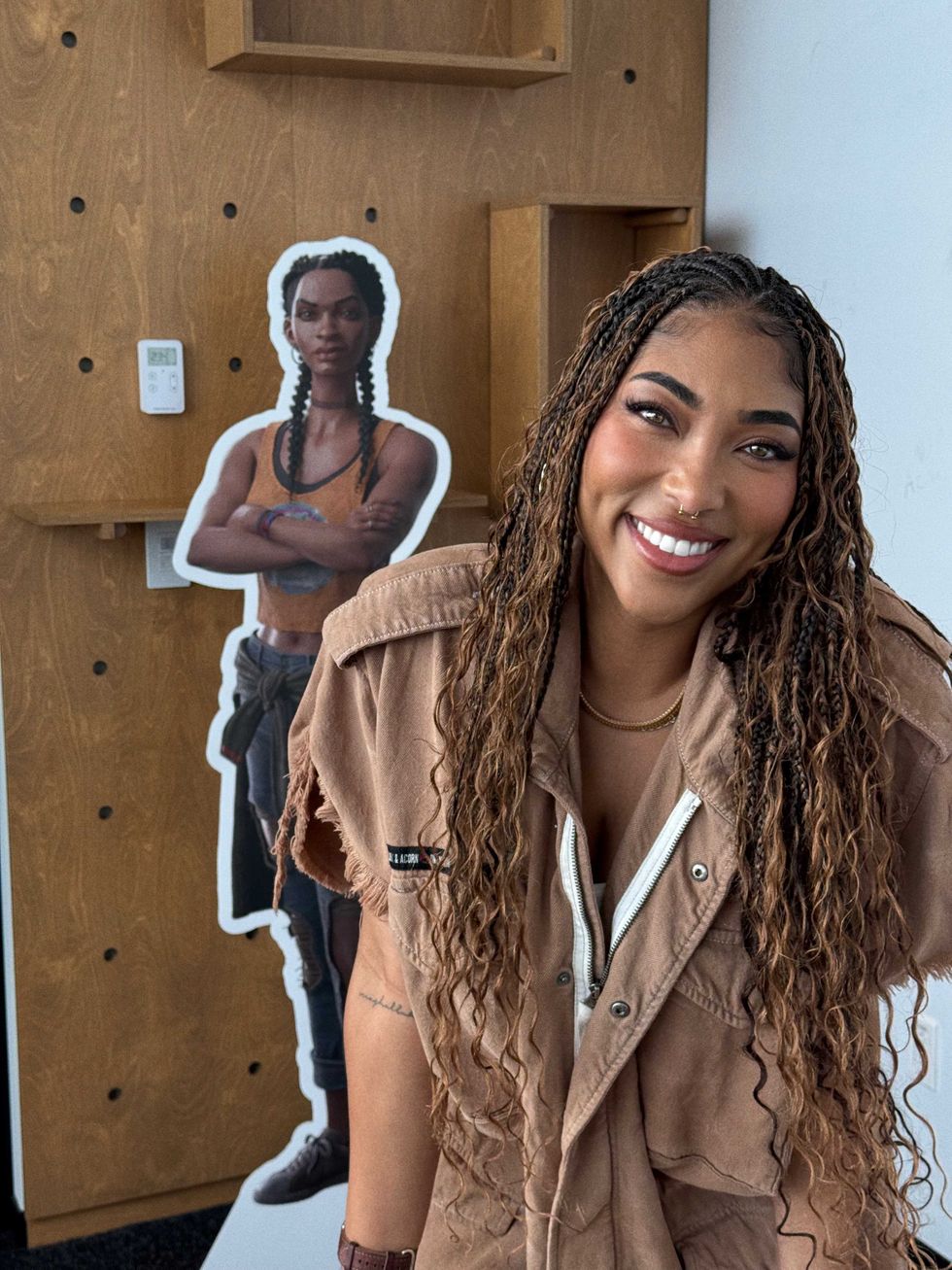 An image of Adriyan Rae with a cardboard cutout of Hazel from South of Midnight in the background
