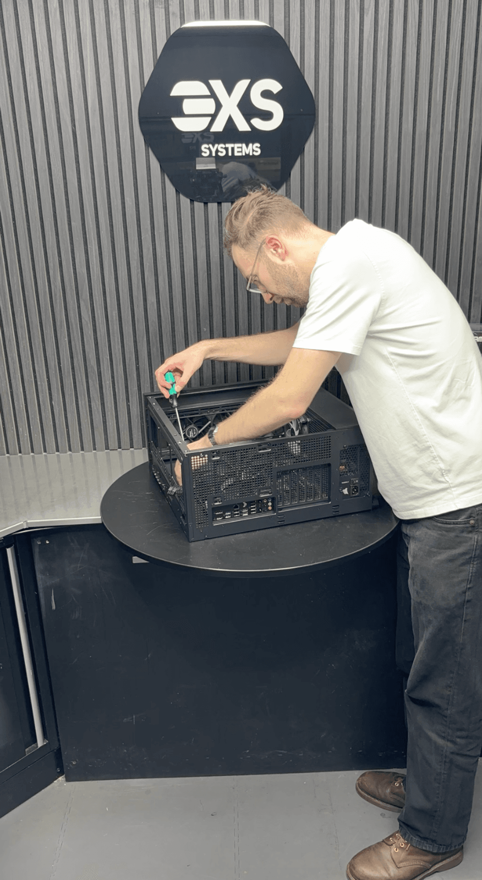 An image of Jake Brigstock screwing in the motherboard to a PC case