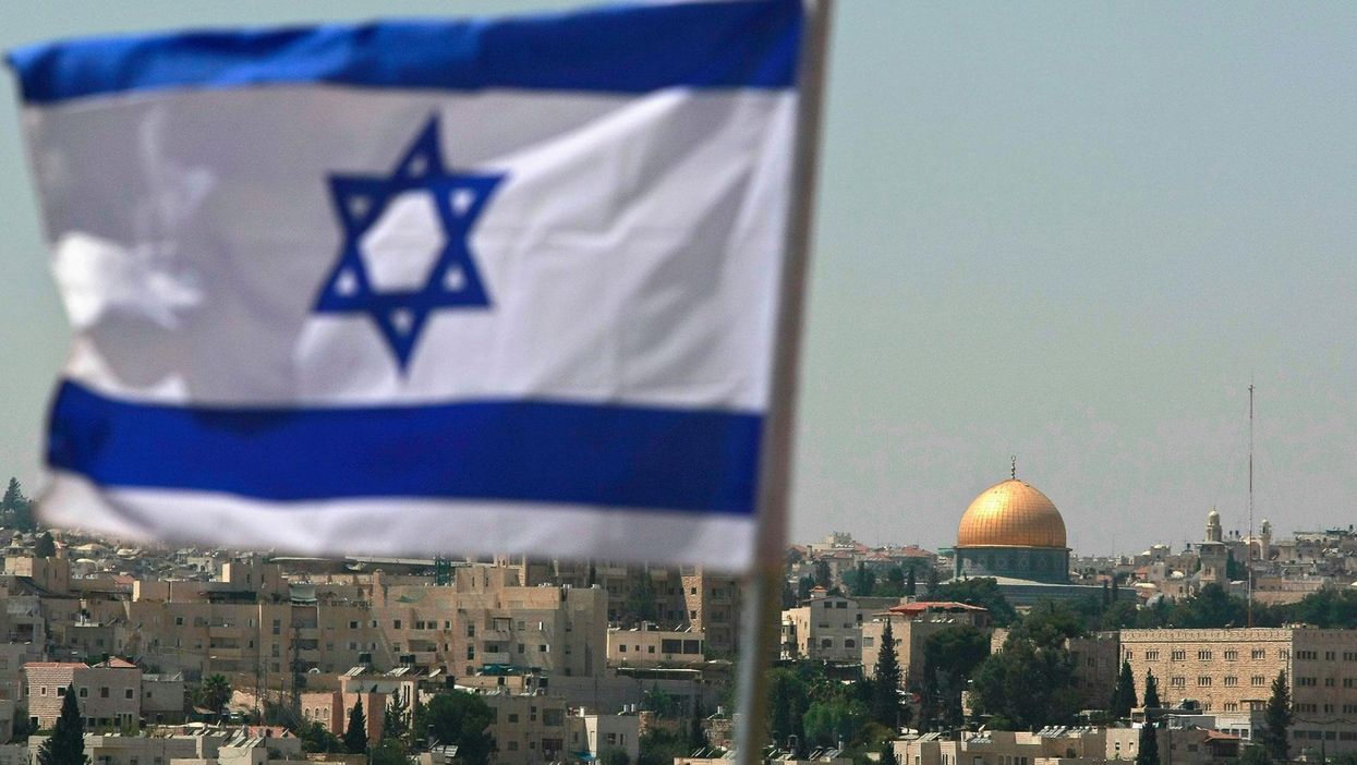 An Israeli flag flies from the Kidmat Zion Jewish settlement community on the outskirts of the Arab village of Abu Dis, where the Old City with its golden Dome of the Rock Islamic shrine is seen in the background, 18 August, 2008 in East Jerusalem, Israel