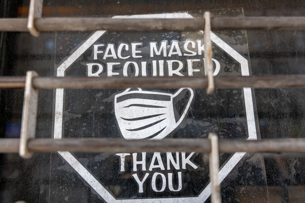 An old sign in a window of a closed business asks customers to wear a mask to prevent the spread of COVID-19 as the nation marks the fifth anniversary of the Covid-19 pandemic on March 13, 2025 in New York City