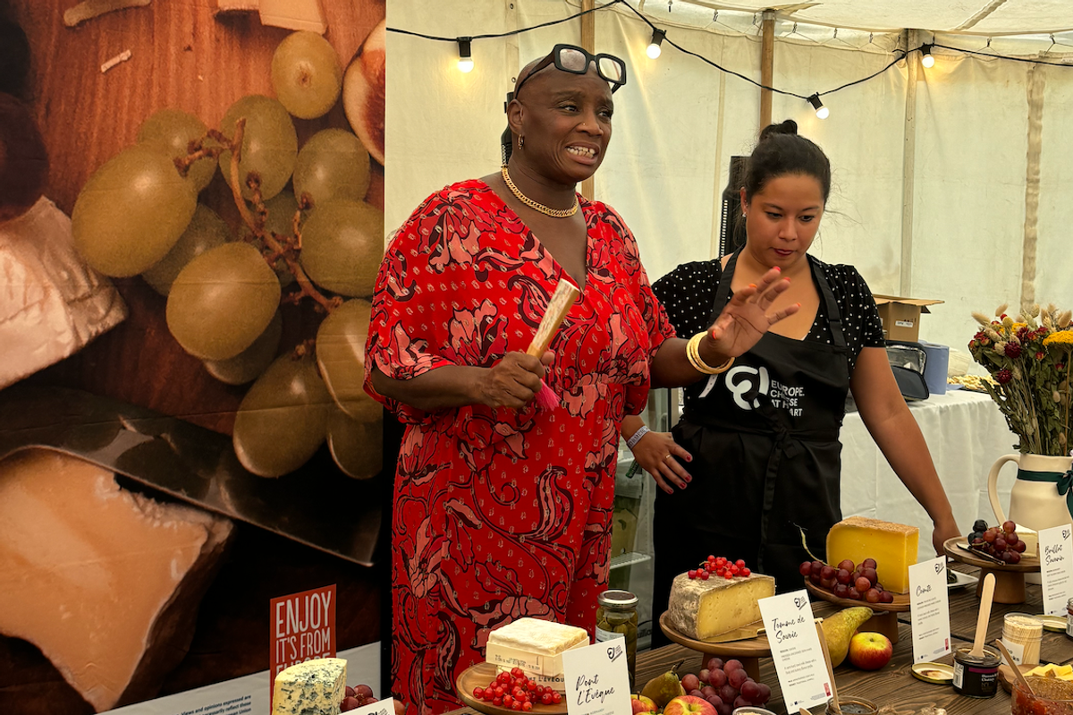 Andi Oliver and Emma Young stand behind a table of French cheese as they explain how each one was made