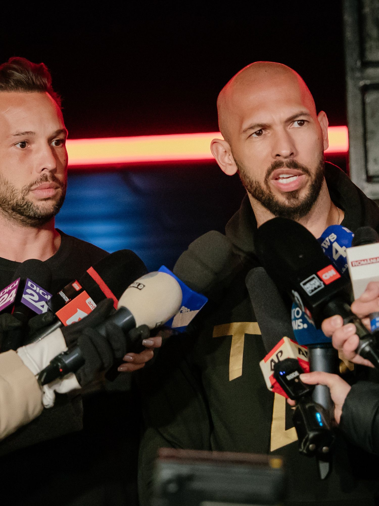 Andrew Tate and his brother Tristan Tate talk to the media outside their residence on March 23, 2025 in Bucharest, Romania